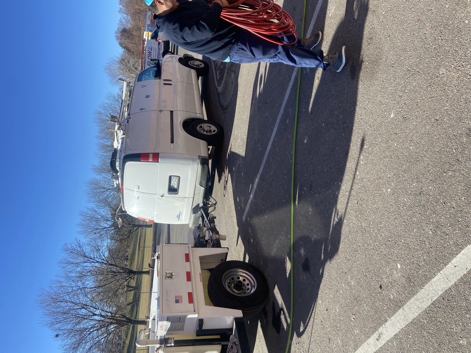 Sewer jetting trailer on site with technician in hi-vis vest