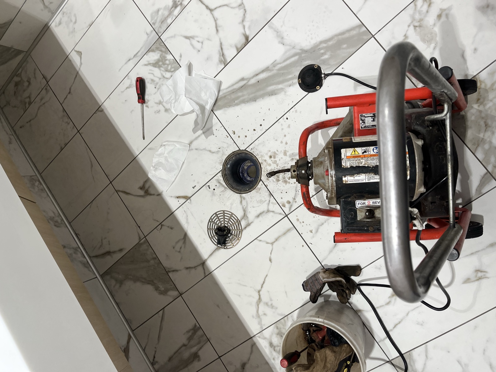 Drain snake machine set up on tile bathroom