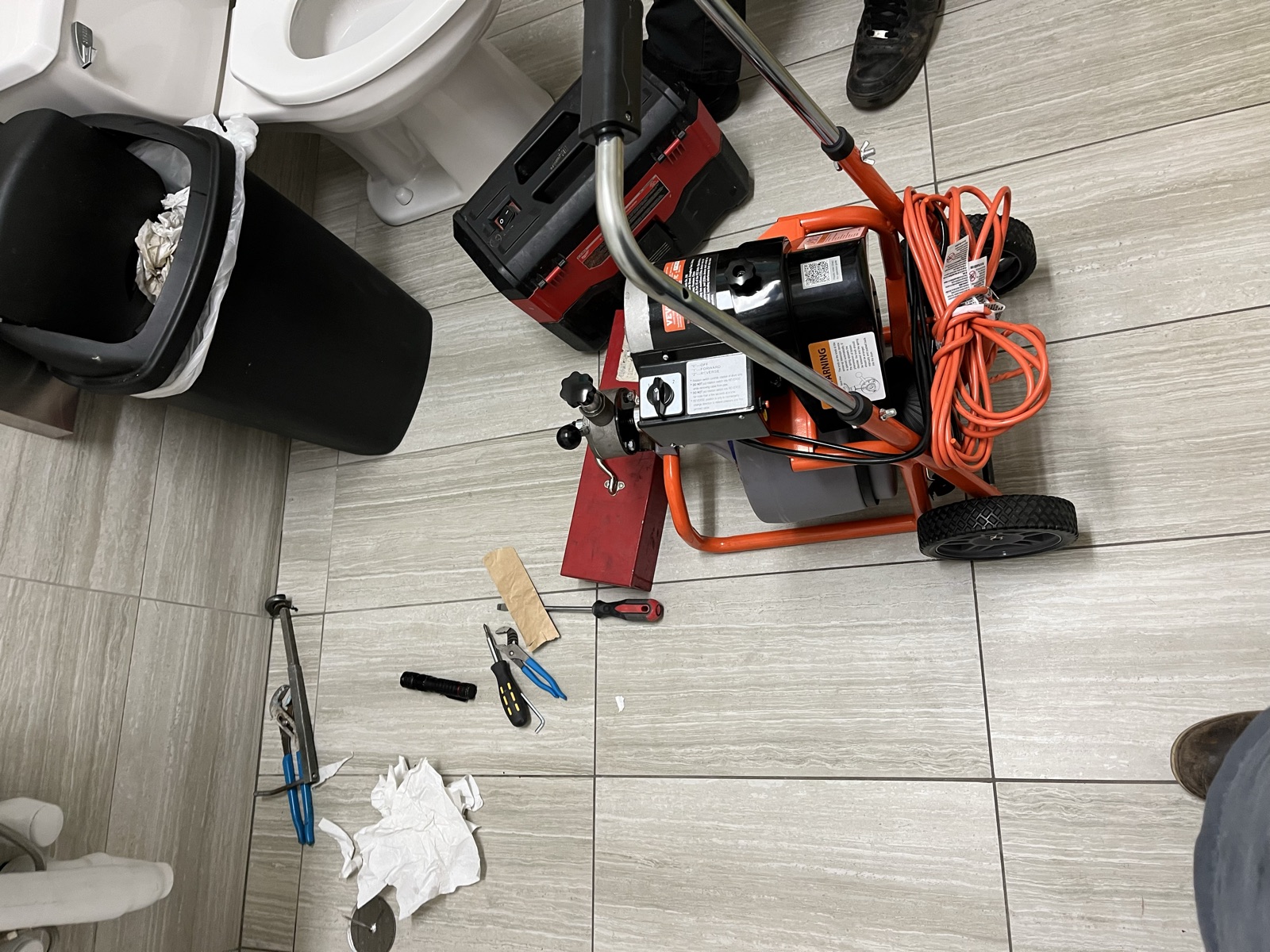 Drain cleaning machine next to a toilet